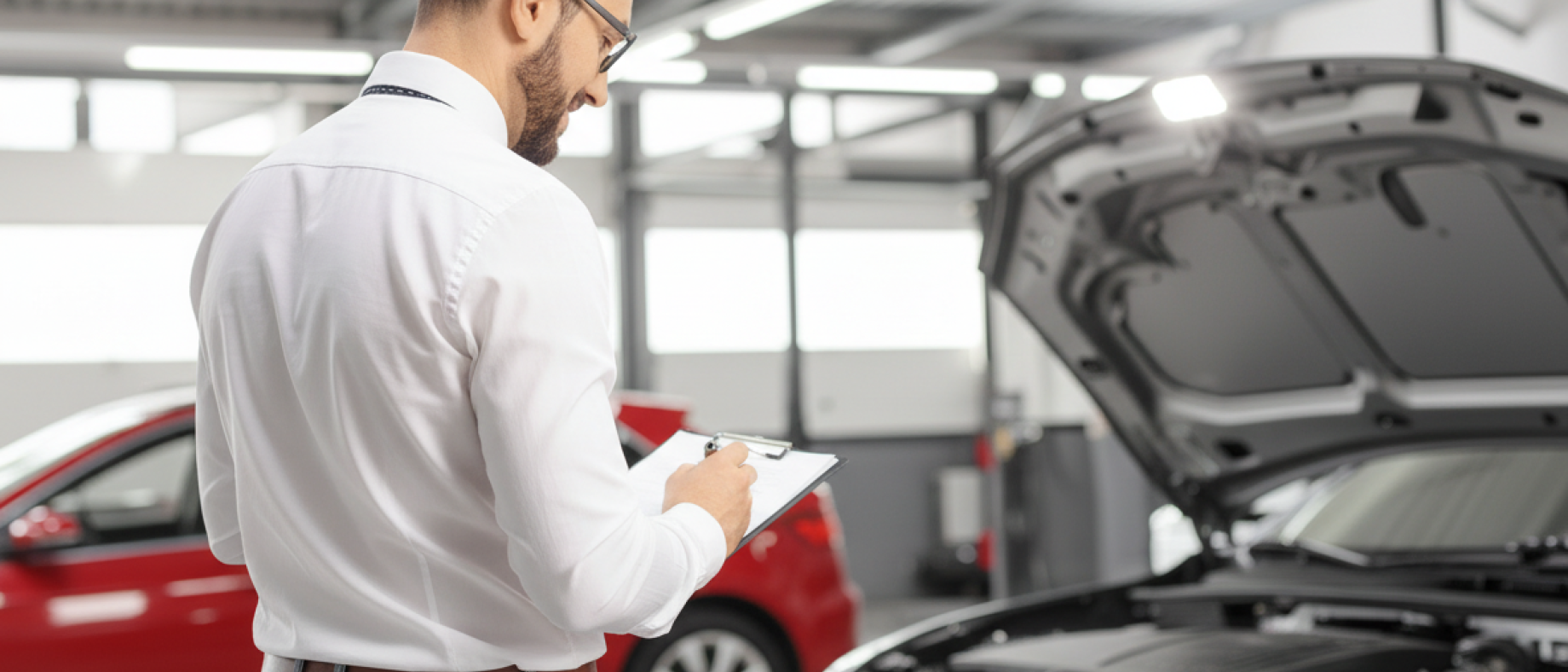 Une personne de dos regardant le moteur d'une voiture