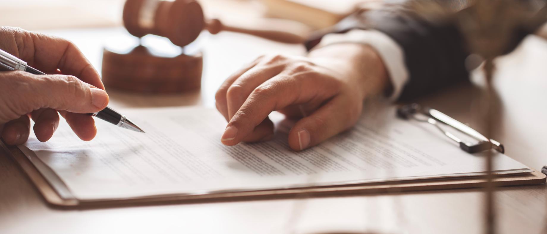 Scène de signature d'un document, une main indiquant un endroit et une autre main tenant un stylo