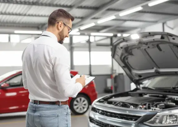 Une personne de dos regardant le moteur d'une voiture